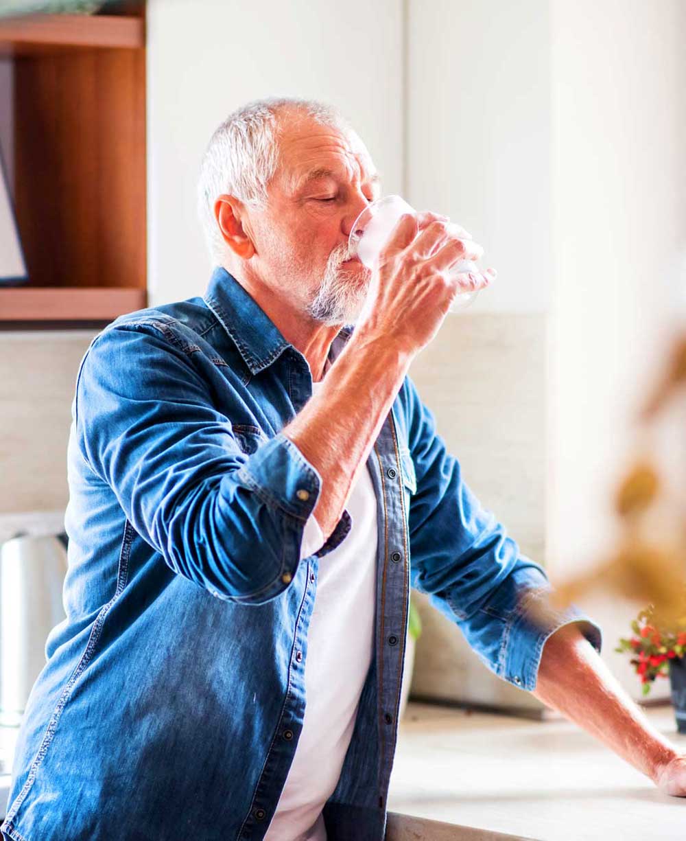 Senior man drinking water at home & staying hydrated